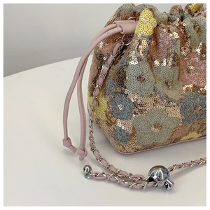 Dettaglio borsa a secchiello con paillettes, motivi floreali e coulisse rosa