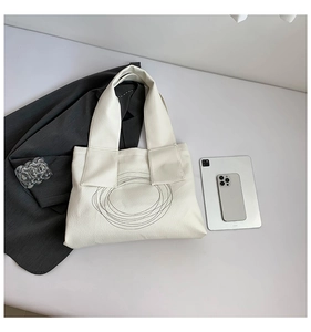 Flat lay of off-white tote bag with circular patterns, showing spacious daily commute capacity