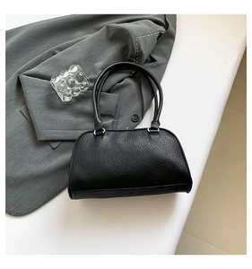 Detail view of black lychee texture faux leather handbag with silver rings on grey blazer