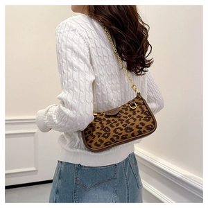 Detail of leopard print underarm bag with gold chain strap worn with casual knitwear