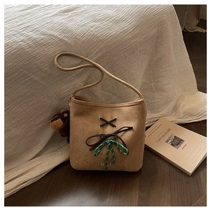 Close-up of brown suede bucket bag with woven bow detail and cute bear keychain