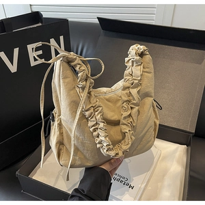 Detailopname van beige geplooide cloud bag met trekkoord in een geschenkverpakking