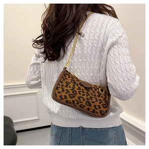 Detailed back view of a leopard print underarm bag with gold chain strap on a model