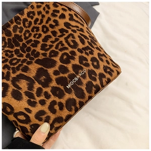 Close-up detail of leopard print faux fur bucket bag with gold logo and leather strap
