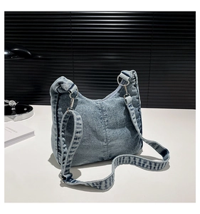 Detail of blue washed denim hobo bag with silver O-ring and adjustable wide shoulder strap