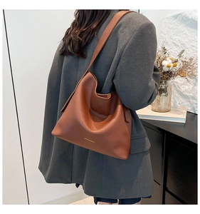 Detailed view of caramel brown leather bucket bag on a model in a grey blazer jacket