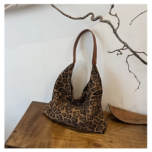 Close-up of leopard print tote bag texture and brown leather strap on wooden surface