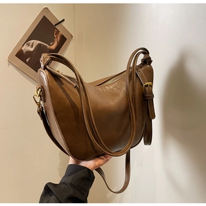 Detail view of brown hobo shoulder bag featuring adjustable strap and bronze hardware