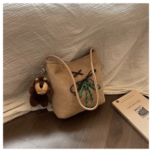 Detail of suede shoulder bag with VILLA embroidery and a cute brown puppy plush charm