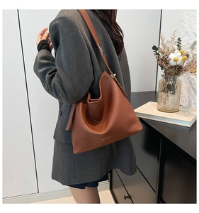 Close-up of caramel brown pebble leather bucket bag with adjustable shoulder strap and logo