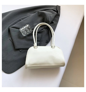 Detail view of white underarm bag with lychee texture on dark grey fabric backdrop