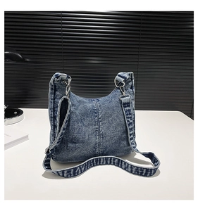 Detail of dark blue washed denim crossbody bag with silver metal ring and lobster clasp
