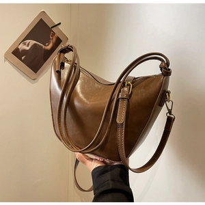 Close-up of retro brown leather bucket bag with decorative knotted straps and gold hardware