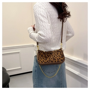 Detailed close-up of leopard print crossbody bag with gold chain on model's back