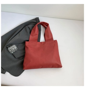Detailed top view of a brick red tote bag featuring fine leather texture on white backdrop