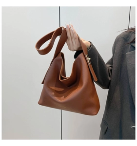 Macro detail of caramel leather tote bag showing fine texture and golden logo