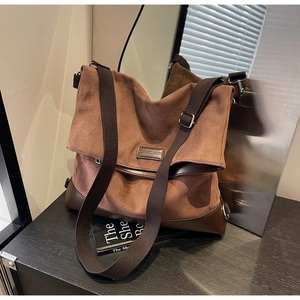Detail of a large brown suede tote bag with reinforced leather base and canvas strap