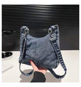 Detail of vintage washed denim underarm bag with silver metallic rings and wide strap