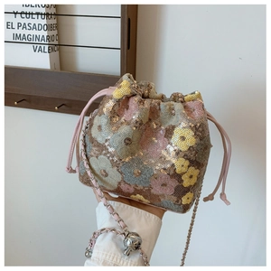 Dettaglio delle paillettes floreali e della coulisse in pelle rosa sulla borsa