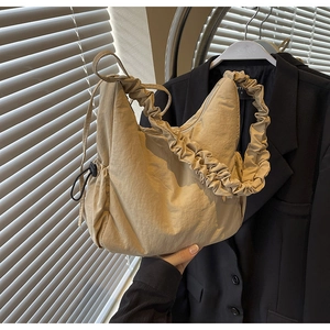 Detail van beige nylon cloud bag met geplooide handgreep en zwart trekkoord slot