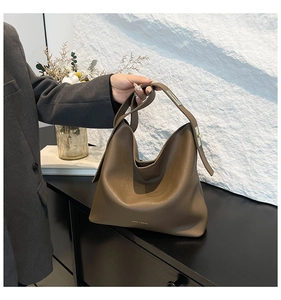 Close-up of brown synthetic leather tote showing its texture and golden logo detail