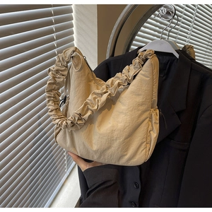 Detail van beige cloud bag met geplooide schouderband en gladde nylon structuur