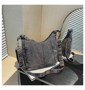 Detail of gray washed denim hobo bag with adjustable wide strap and metallic buckles