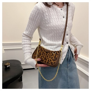 Detail of leopard print crossbody bag with gold chain strap and leather trim accents