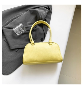 Top view of pale yellow Boston bag with dual handles on a white glossy background