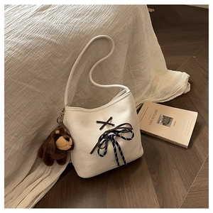 Detail of cream felt bucket bag with brown straps and cute puppy plush charm pendant