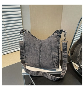 Detailed view of gray denim crescent bag with adjustable strap and silver metal hardware