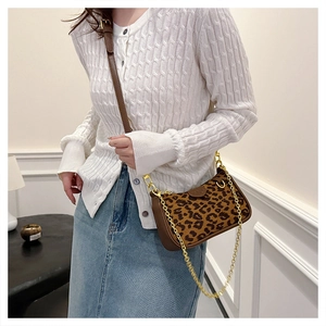 Leopard print rectangular shoulder bag with golden chain strap on a white knit sweater