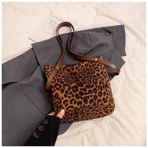 Detail of leopard print bucket bag with brown leather handles on a grey suit jacket