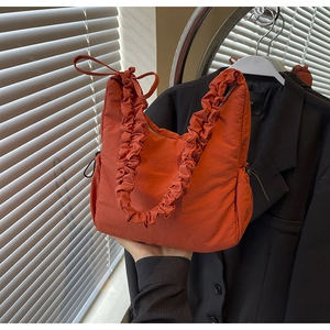 Detail van de steenrode gewatteerde cloud bag met trekkoordplooien en strikschouderband