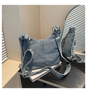 Detail of light blue washed denim crescent bag with silver adjustable buckle strap