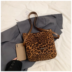 Detailed close-up of leopard print bucket bag with brown leather handles and gold logo