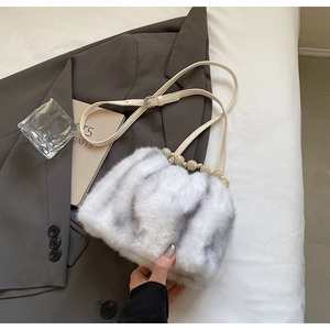 Detail of faux fur striped bucket bag with cream beaded handle and leather strap