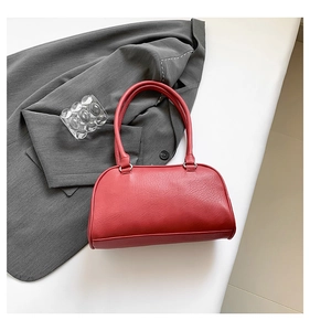 Detail of red pebbled leather underarm bag with silver hardware and grey blazer decor