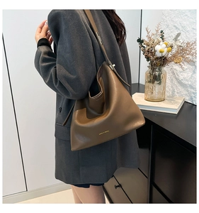 Detail of deep brown pebble leather hobo bag with gold logo on a female model