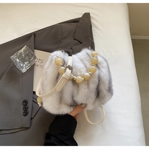 Close-up of faux fur handbag with grey stripes, amber bead handle and leather strap