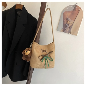 Close-up of khaki suede bucket bag with brown straps and a cute plush dog pendant charm