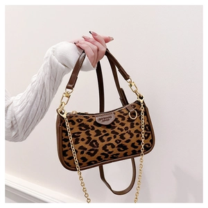 Detail of leopard print hobo bag featuring dark brown leather trim and golden metal chain strap