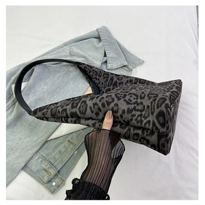 Close-up of leopard print tote bag with black leather strap on white sheet background