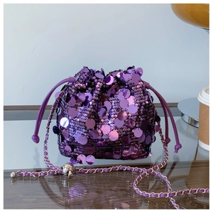 Dettaglio ravvicinato della borsa a secchiello con paillettes viola e tracolla a catena