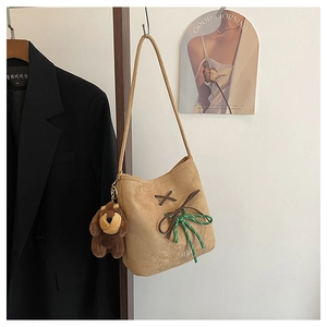 Detail of suede bucket bag with decorative cross lacing and cute puppy charm on the handle