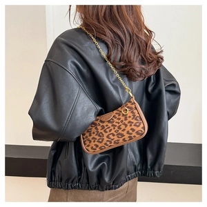 Detail view of leopard print underarm bag with gold chain strap on black leather jacket