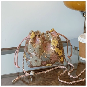 Dettaglio borsa a secchiello con paillettes rosa, motivi floreali e catena oro