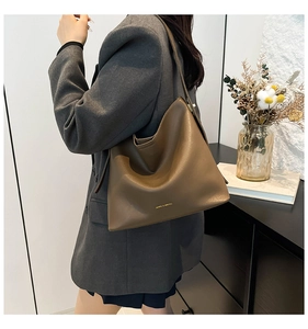 Detail view of the deep brown leather bucket bag showing its premium texture and gold logo