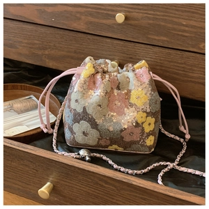 Dettaglio della borsa a secchiello di paillettes con fiori rosa e tracolla a catena