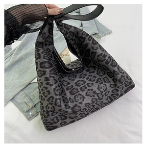 Detail of grey leopard print tote bag with black shoulder strap over casual denim jacket